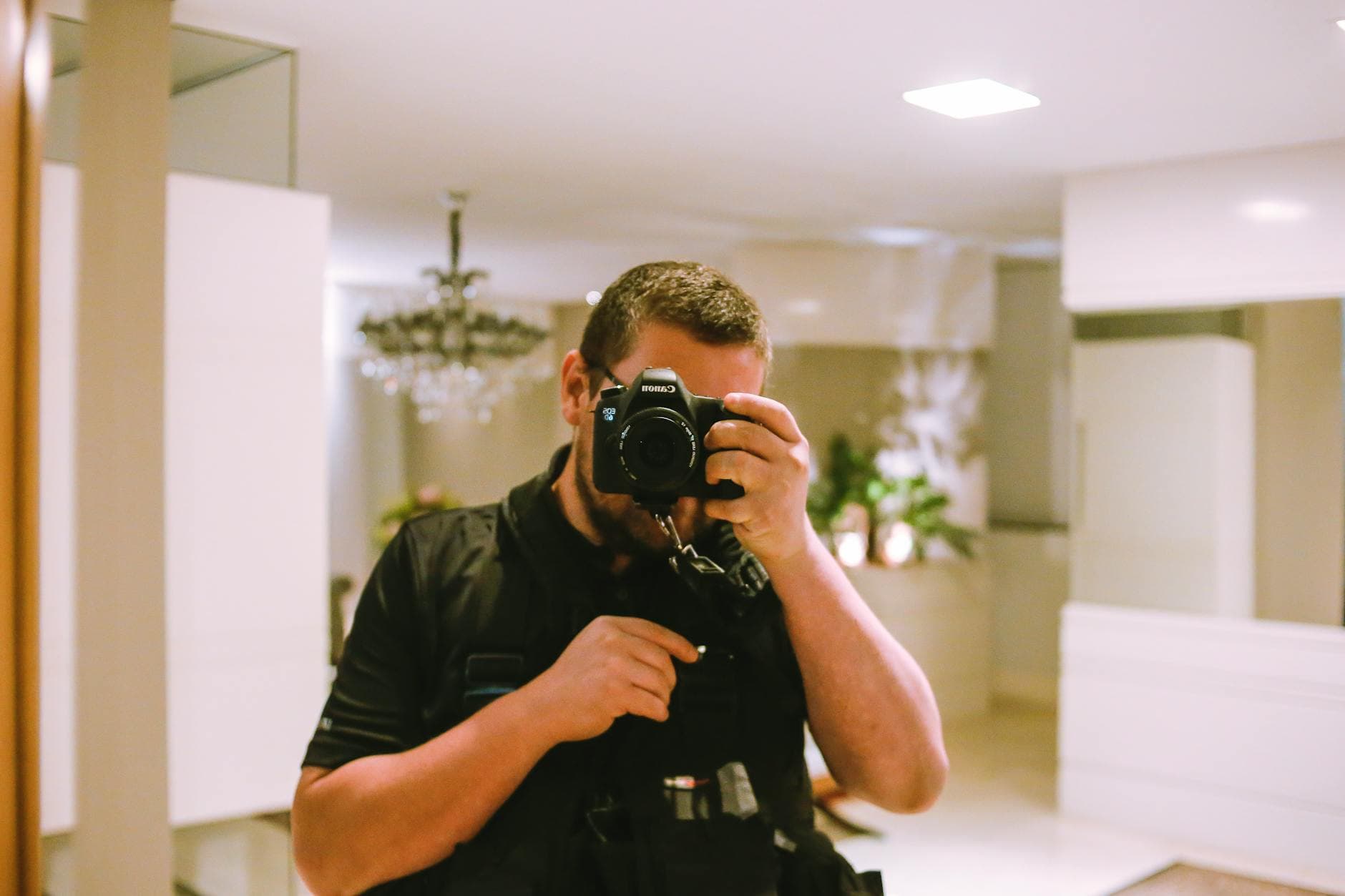 A photographer takes a photo in a stylish indoor setting with a Canon DSLR